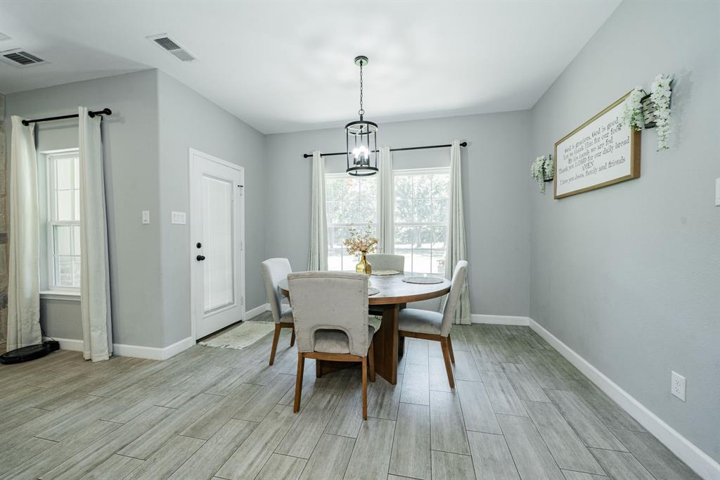 7679 Caddo Creek Road Quinlan, TX 75474 - Photo 13 of 28 a dining room with wooden floor a chandelier a wooden table and chairs