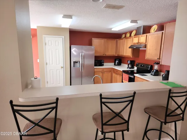 a kitchen with stainless steel appliances a refrigerator a stove a sink and chairs