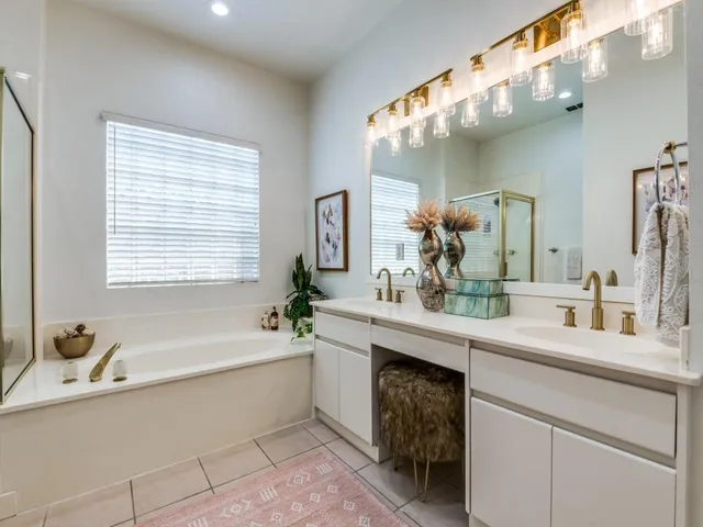 a bathroom with a bathtub a double vanity sink and mirror