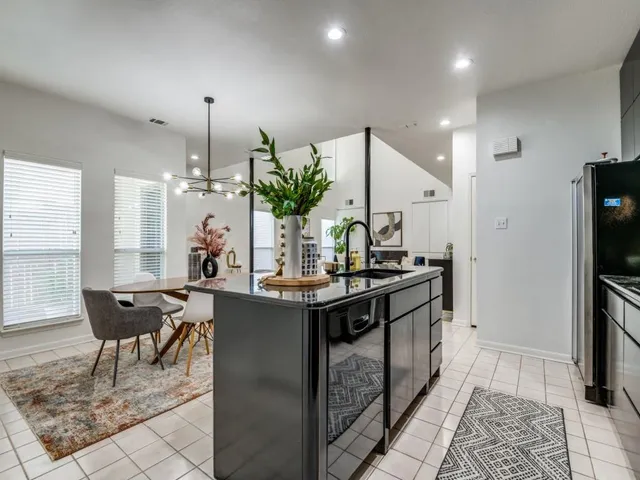 a kitchen with stainless steel appliances kitchen island granite countertop a table chairs in it and wooden floors