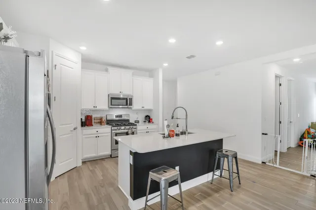 a kitchen with stainless steel appliances a sink a stove a refrigerator cabinets and wooden floor