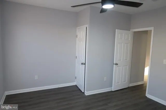 an empty room with wooden floor closet and windows