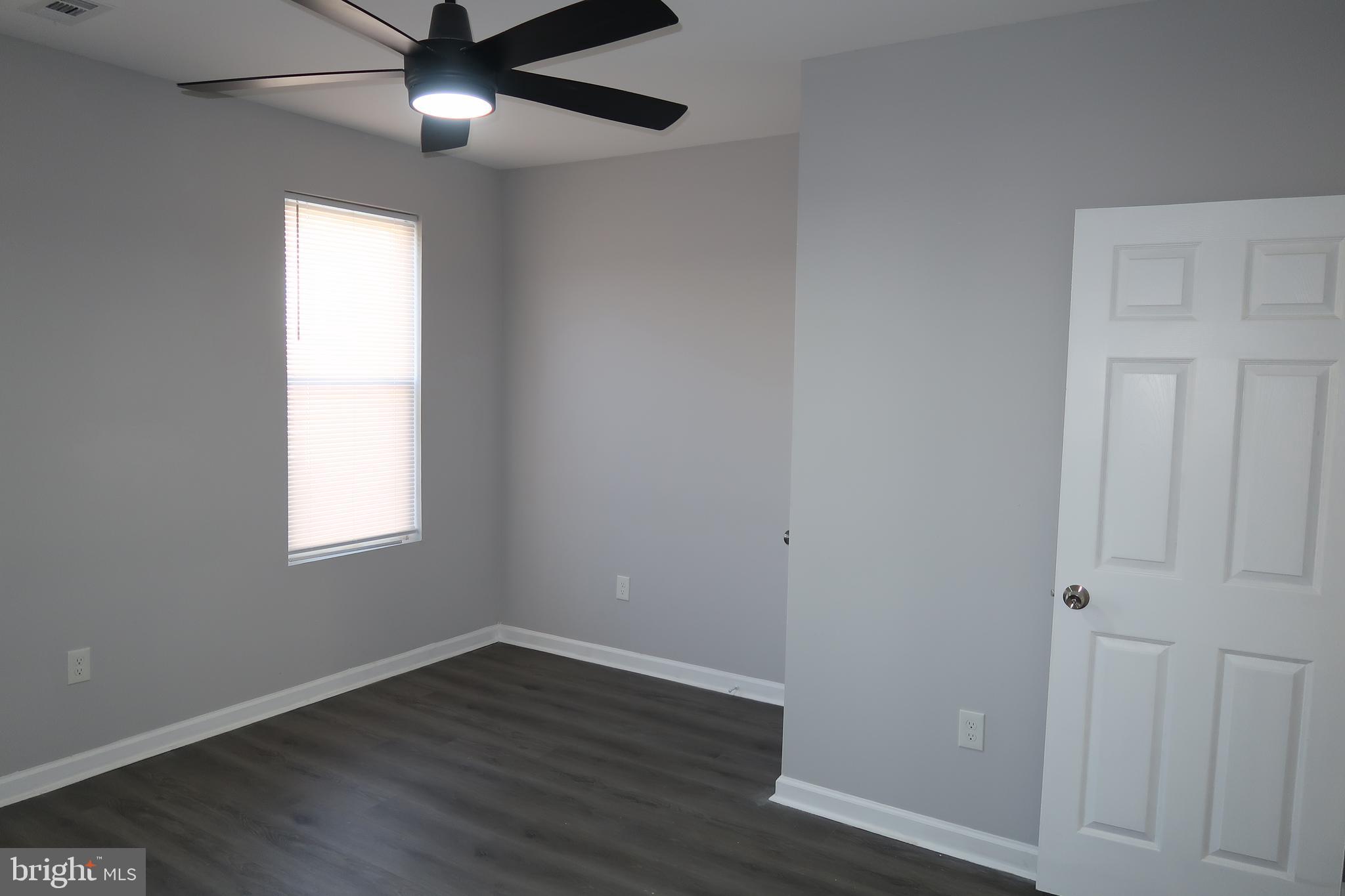2833 Brendan Avenue, Unit 2 Baltimore, MD 21213 - Photo 7 of 17 an empty room with wooden floor ceiling fan and windows