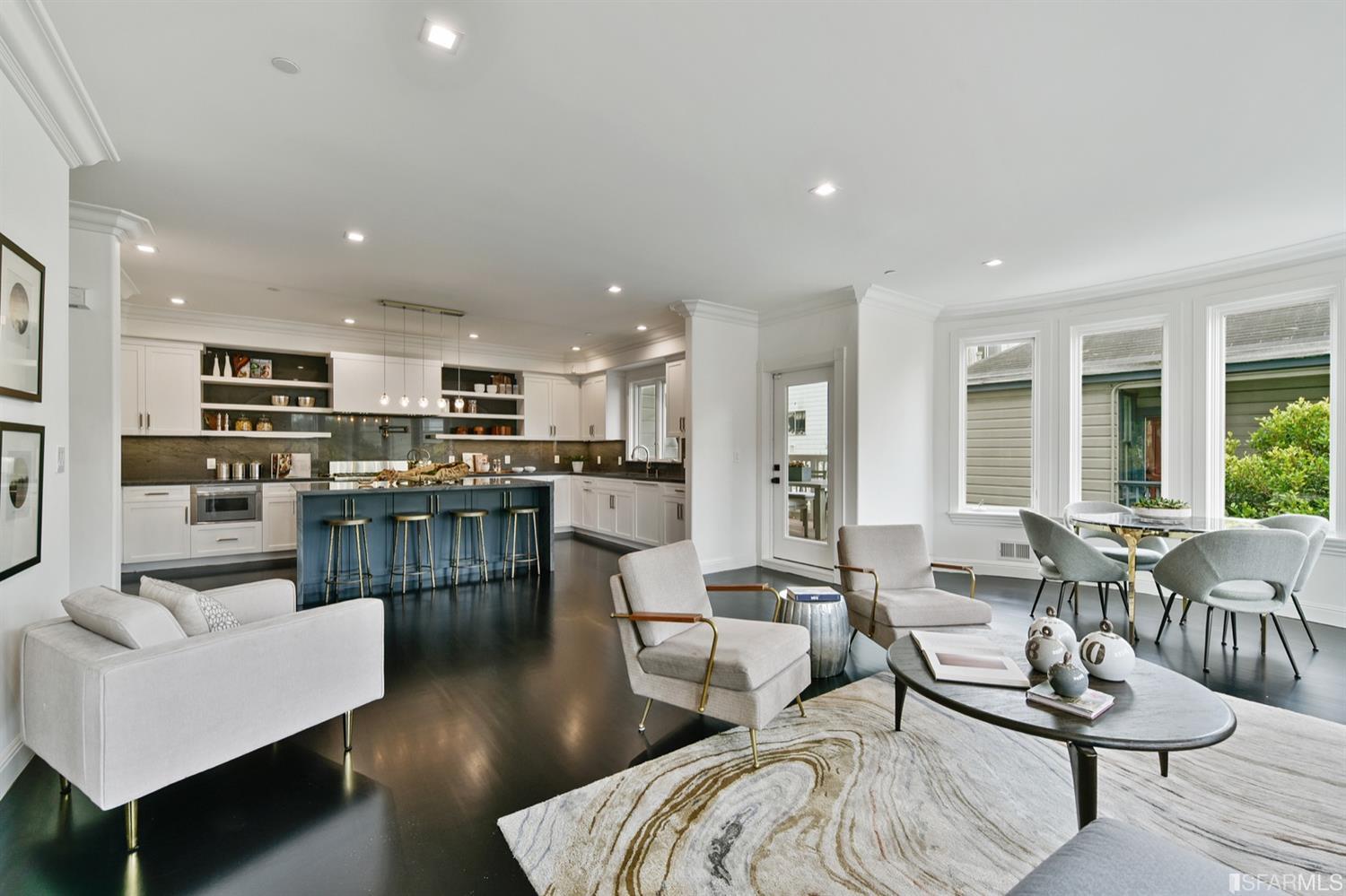 a living room with furniture kitchen view and a wooden floor