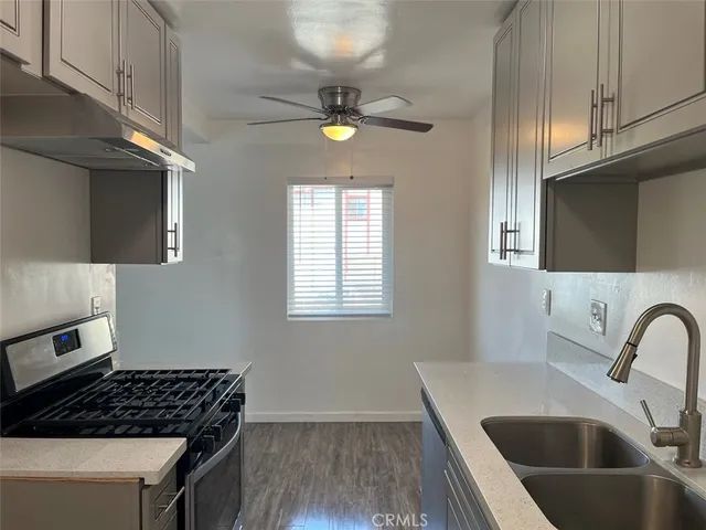 a kitchen with a sink a stove cabinets and a window
