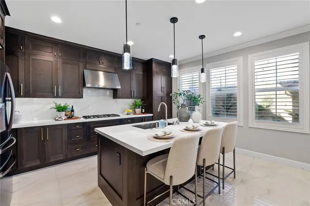 a kitchen with stainless steel appliances granite countertop a sink a stove a refrigerator and wooden floor