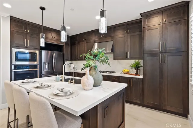 a kitchen with stainless steel appliances kitchen island granite countertop a refrigerator a sink a stove and island