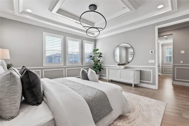 a bedroom with a bed a mirror on dresser and a chandelier