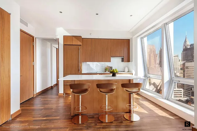 a view of a kitchen with kitchen island granite countertop wooden floor and white cabinets