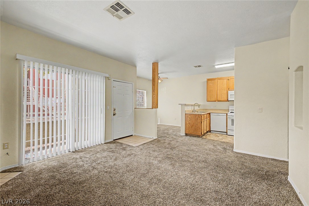 4730 East Craig Road, Unit 1091 Las Vegas, NV 89115 - Photo 6 of 23 Sliding glass doors open from the carpeted living area toward the adjacent kitchen.