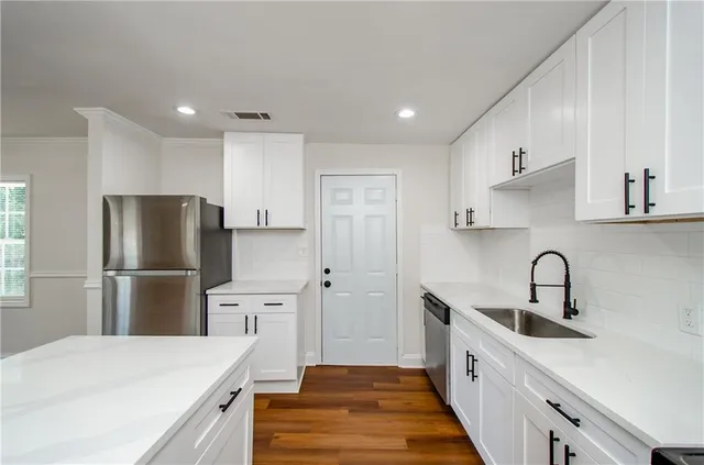 a kitchen with a refrigerator a sink and white cabinets