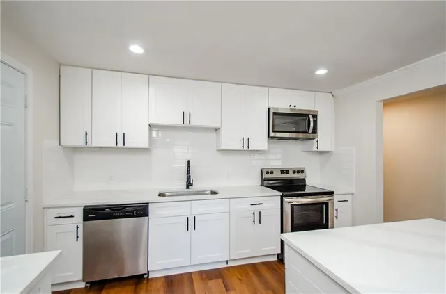 a kitchen with white cabinets stainless steel appliances and sink