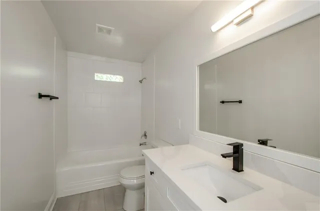 a bathroom with a sink a toilet a window and shower