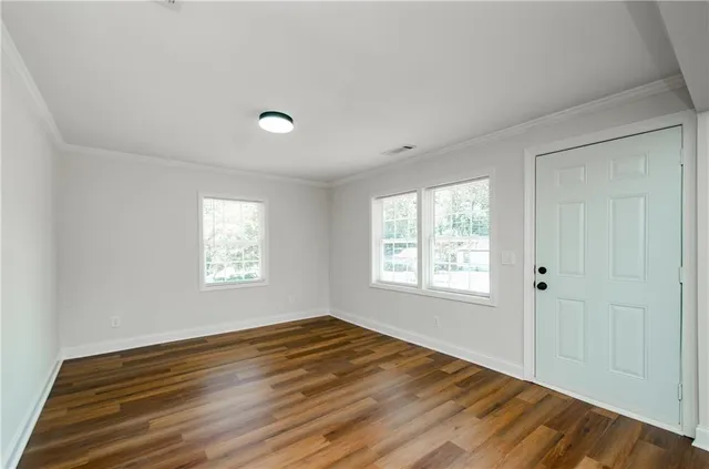 a view of an empty room with wooden floor and a window