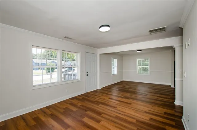 a view of an empty room with wooden floor and a window