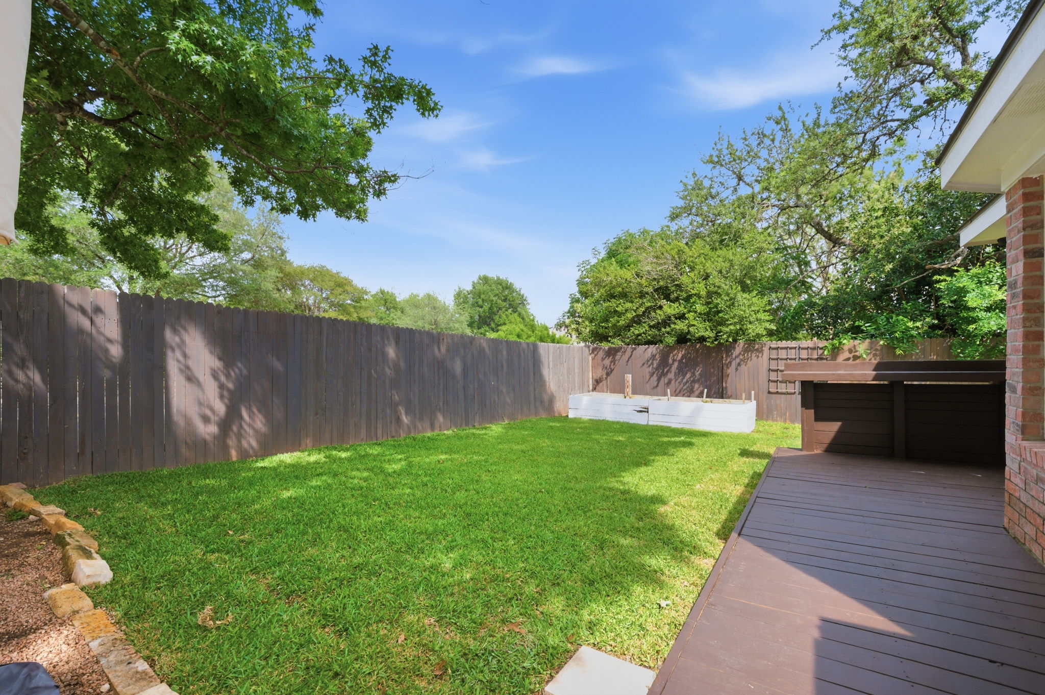9024 Heiden Lane Austin, TX 78749 - Photo 24 of 28 Private backyard featuring a composite deck, lush green lawn, full privacy fencing, and a built-in raised planter bed