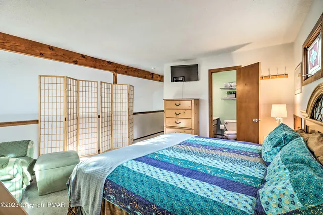 a bedroom with a bed dresser and a large window