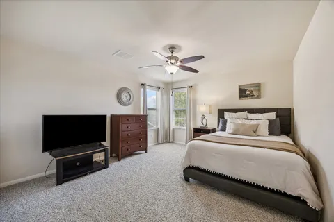 a spacious bedroom with a bed and a flat screen tv