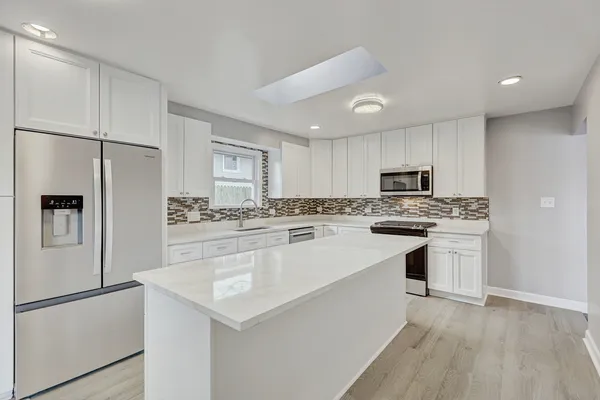 a kitchen with white cabinets and white appliances
