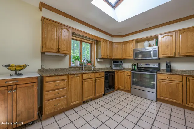 a kitchen with stainless steel appliances kitchen island granite countertop a stove a sink and a refrigerator