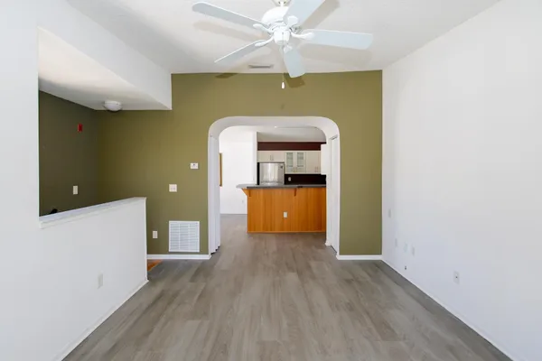 an empty room with wooden floor chandelier and windows