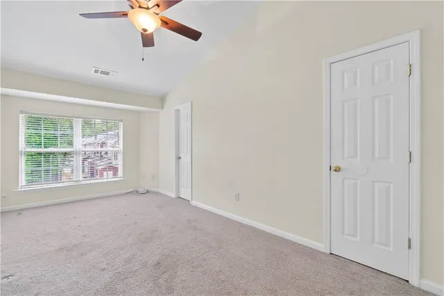 an empty room with chandelier fan and windows