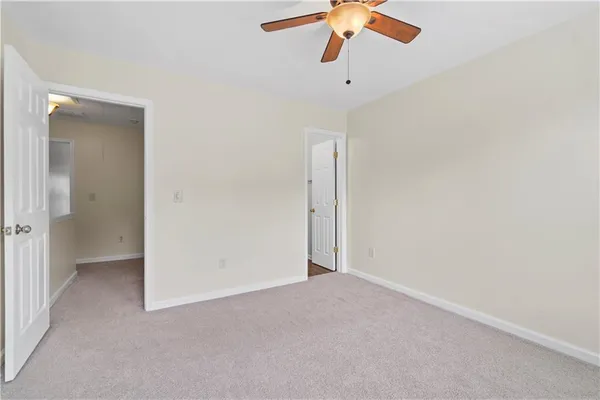 an empty room with a ceiling fan and carpet