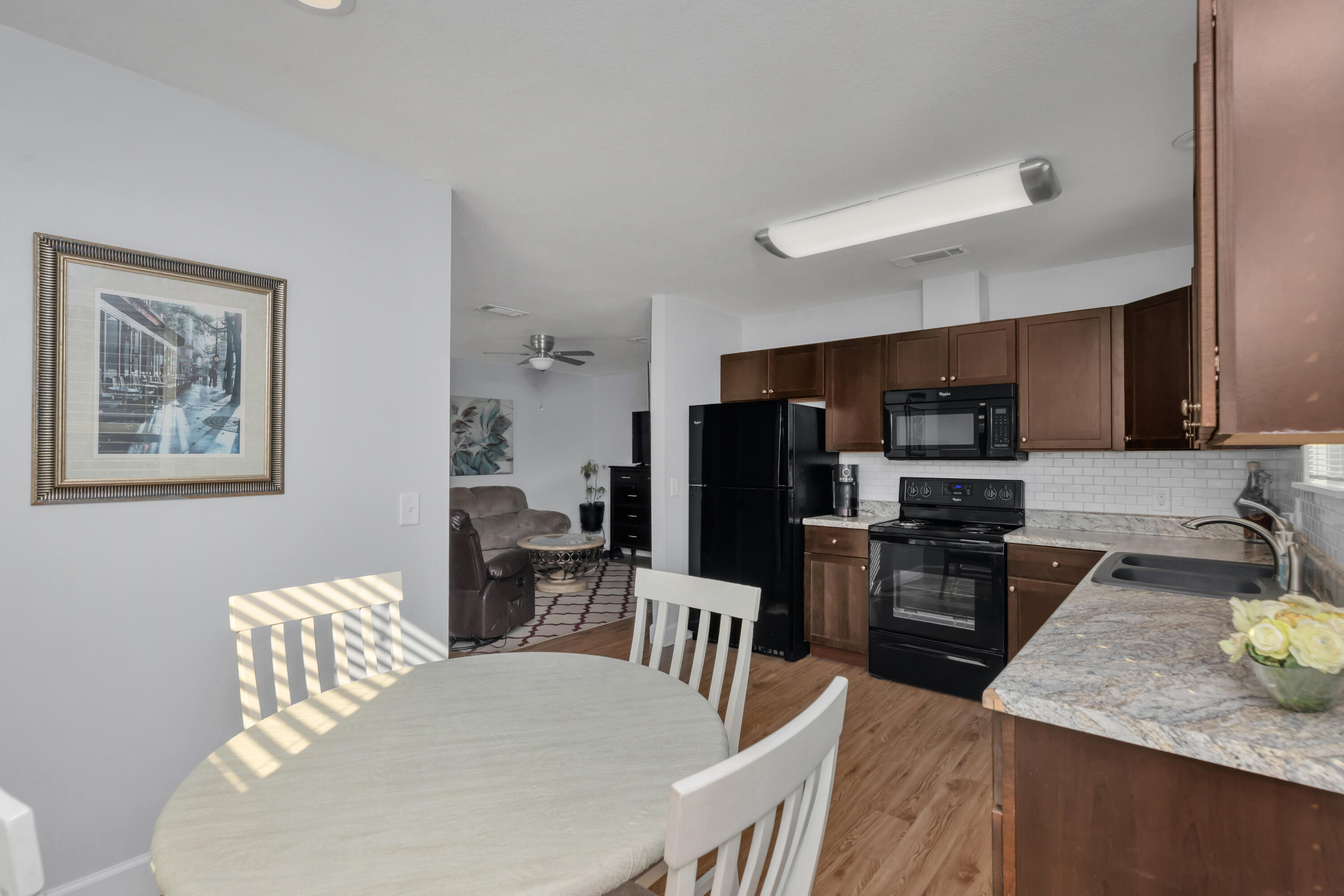 79 6th Street Santa Rosa Beach, FL 32459 - Photo 30 of 42 a kitchen with stainless steel appliances kitchen island granite countertop a refrigerator a stove a sink a dining table and chairs with wooden floor