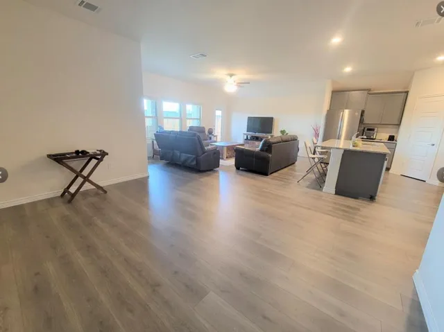 a living room with furniture a flat screen tv and a wooden floor