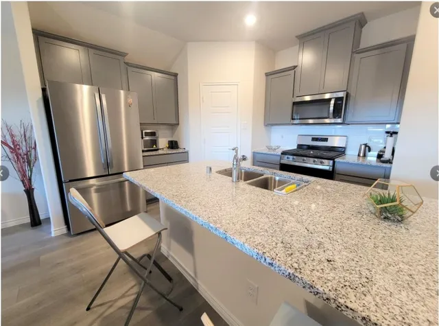 a kitchen with stainless steel appliances granite countertop a refrigerator sink and stove