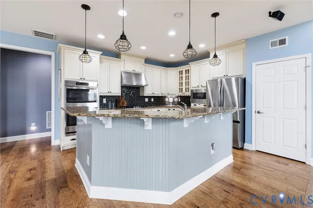 a kitchen with stainless steel appliances granite countertop a refrigerator a oven a sink and a island