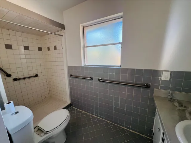 a view of a hallway with wooden floor and a bathroom