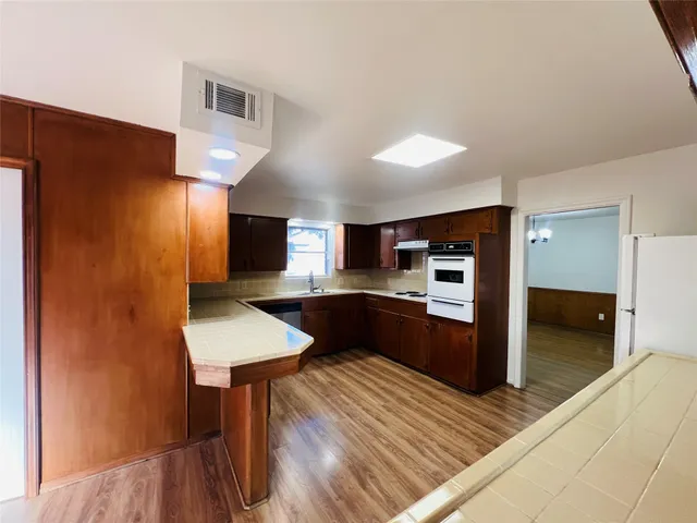 a kitchen with stainless steel appliances a refrigerator and a wooden floor