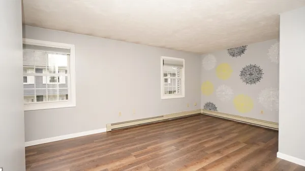 an empty room with wooden floor ceiling fan and windows