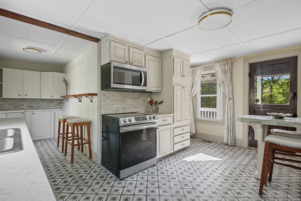 259 Long Plain Road Leverett, MA 01054 - Photo 7 of 39 a kitchen with stainless steel appliances granite countertop a stove top oven a sink dishwasher a dining table and chairs with wooden floor