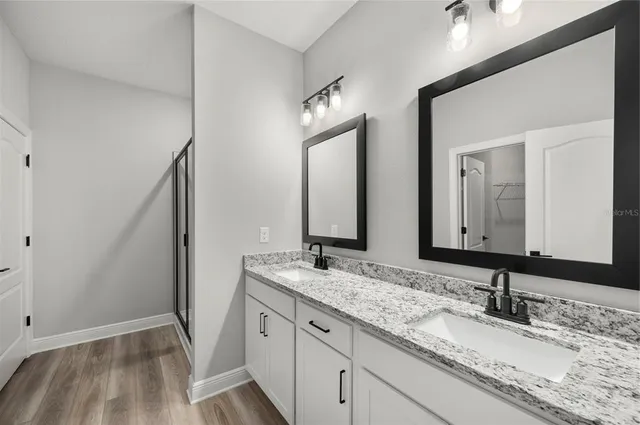 a bathroom with double vanity and a mirror