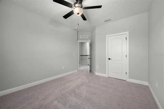 a view of an empty room and a chandelier fan
