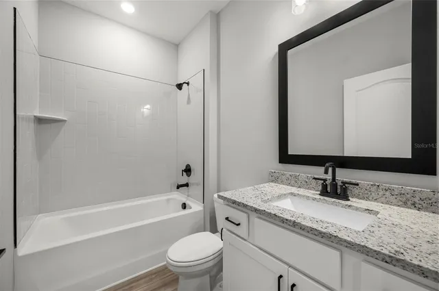 a bathroom with a granite countertop sink a toilet and shower