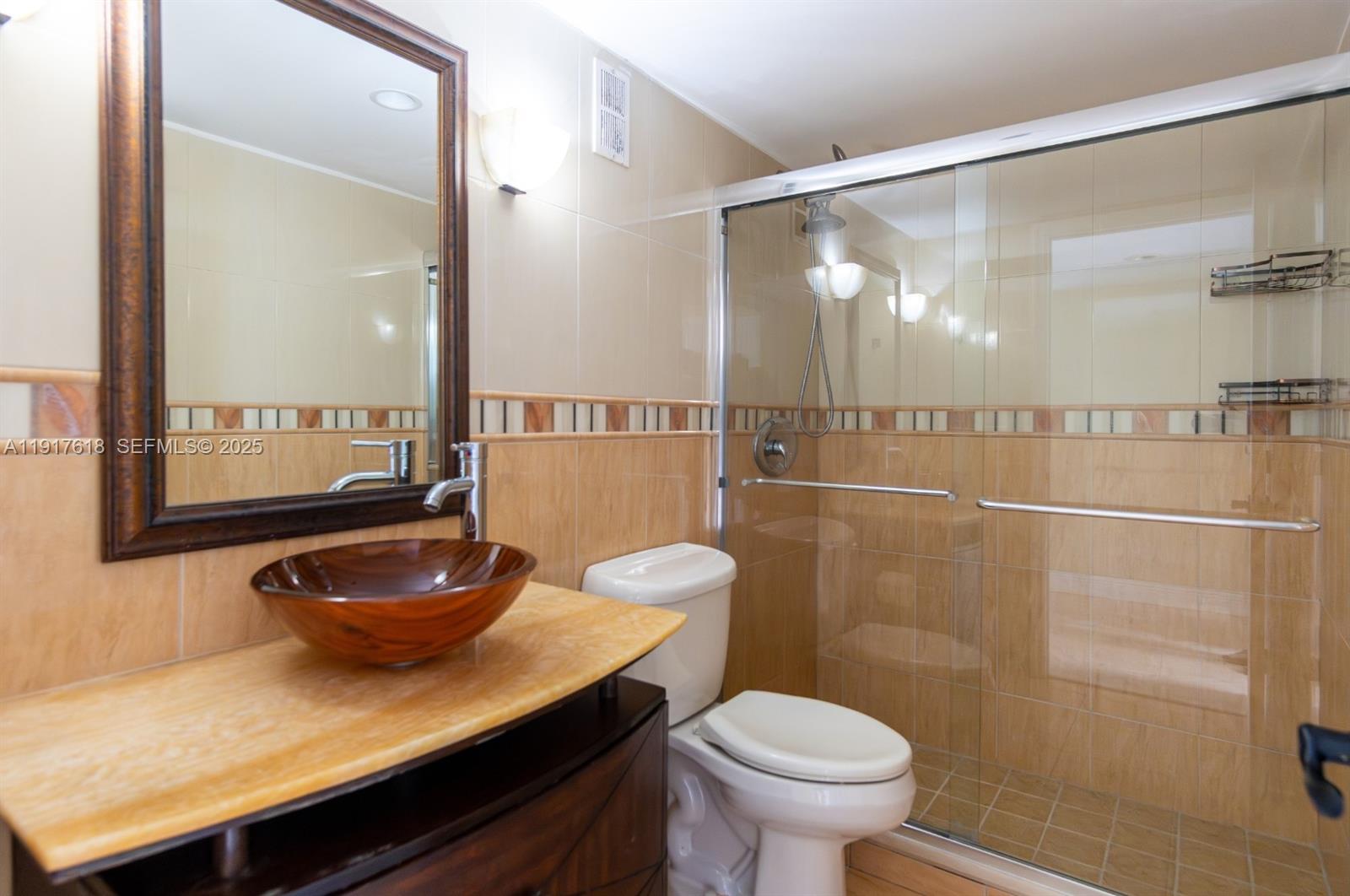 145 Southeast 25th Road, Unit 1003 Miami, FL 33129 - Photo 32 of 43 a bathroom with a granite countertop sink a toilet a mirror and shower