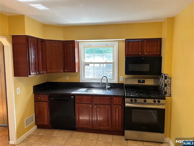 a kitchen with stainless steel appliances granite countertop a stove a sink and a microwave