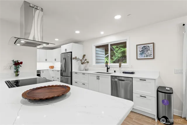 a kitchen with stainless steel appliances a sink cabinets and wooden floor