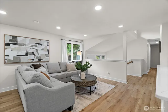 a living room with furniture kitchen view and a wooden floor