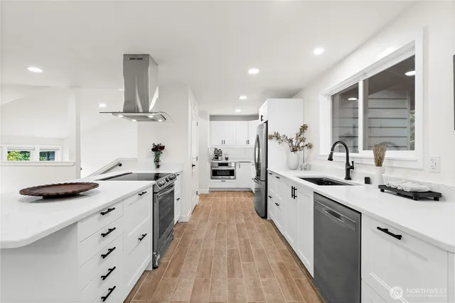 a large kitchen with stainless steel appliances a sink stove and cabinets