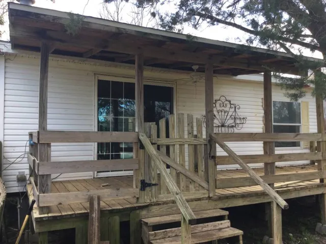 a view of house with wooden stairs and a large tree
