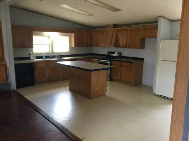 a kitchen with granite countertop a sink cabinets and stainless steel appliances