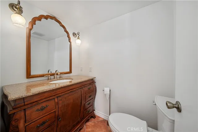 a bathroom with a granite countertop toilet sink and mirror