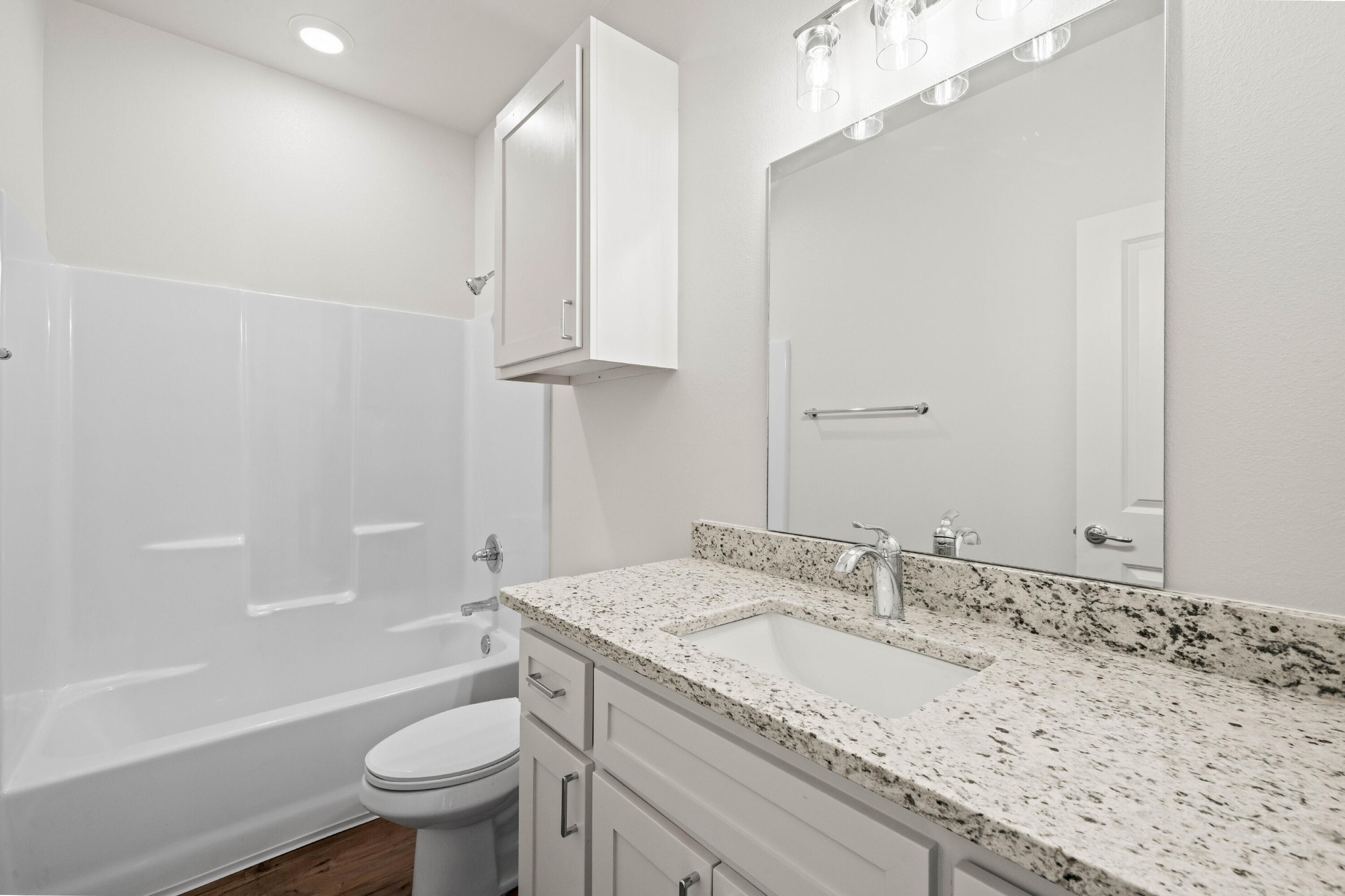 7016 40th Street Lubbock, TX 79407 - Photo 17 of 19 a bathroom with a granite countertop sink a toilet and bathtub