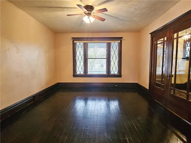 a view of an empty room with wooden floor and a window