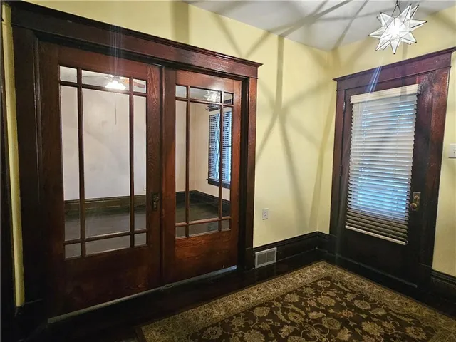 a view of a hallway with wooden floor and a bathroom