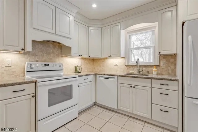 a kitchen with granite countertop white cabinets stainless steel appliances a sink and a window